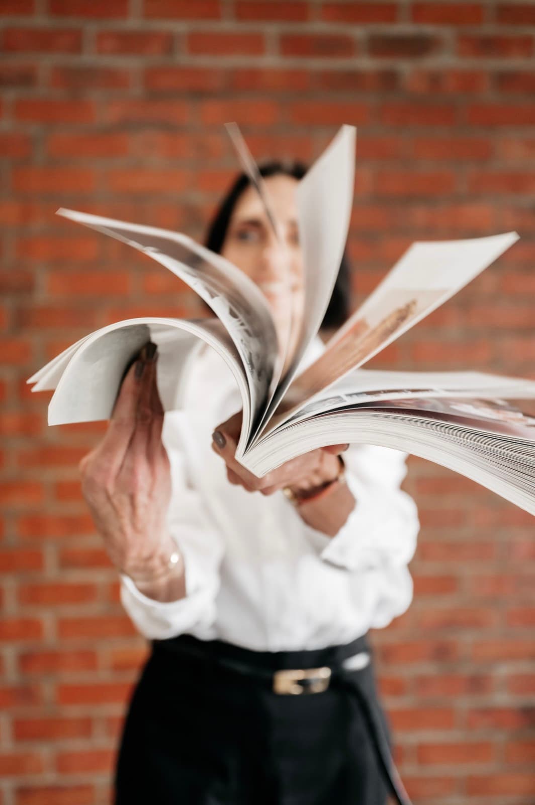 Belinda playfully fanning a workbook open in front of her face