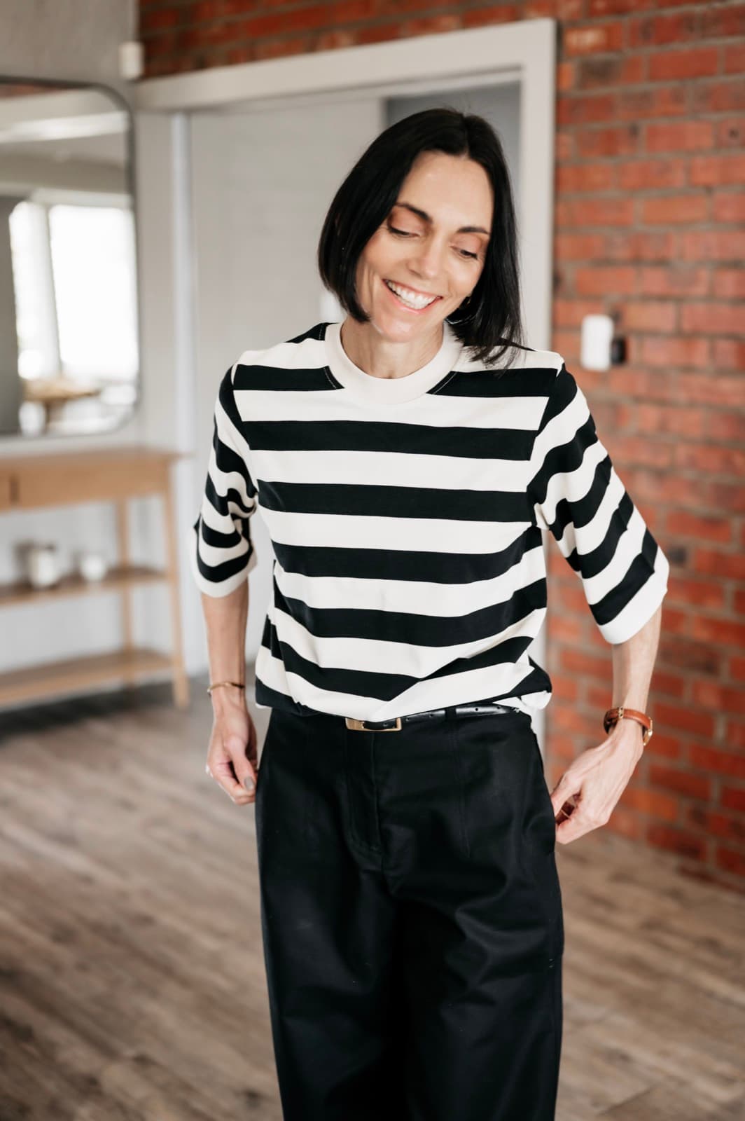 Belinda smiling in a striped top and wide-leg black trousers